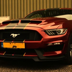 Iconic red Ford Mustang with racing stripes parked outdoors.